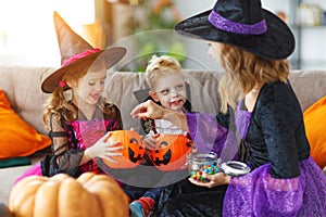 Happy Halloween! mother treats children with candy at home