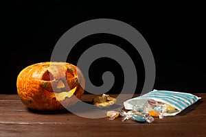 Happy Halloween pumpkin and candies. Trick or treat on a wooden table on a background of old wooden boards