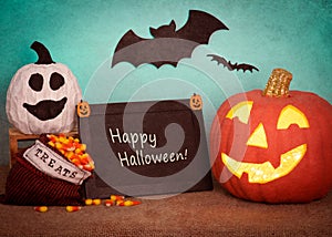 Happy Halloween Pumpkin Still Life Scene with sign board with text, ghost gourd, treats bag, against teal background with bats fly