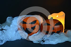 Happy Halloween pumpkin on the web with spiders. Burning candle in the background.
