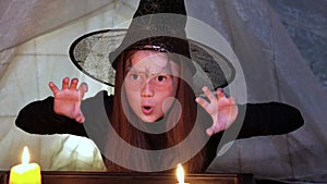 Happy Halloween. Scary kid girl witch saying boo at night with candles
