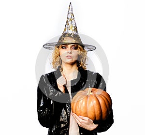 Happy Halloween. Sexy Girl witch with Pumpkin. Traditional food. Serious woman in witches hat and costume with orange
