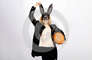 Happy Halloween. Sexy woman in black bunny mask and leather jacket with Halloween pumpkin. Smiling girl in Halloween