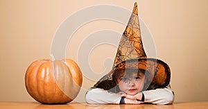 Happy Halloween. Smiling boy in witch hat with halloween pumpkin. Halloween kid in magic hat. Little child in wizard