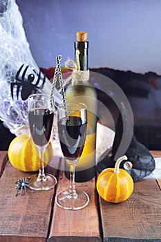 Happy Halloween, still life with red wine cocktail, pumpkins, spiders and cobwebs, illumination, against the backdrop of a landsca