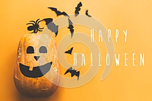 Happy Halloween text, greeting card. Pumpkin with face and black bats, ghost, spider paper decorations on yellow background. Flat