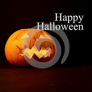 Happy halloween text in white with carved jack o lantern pumpkin on black background