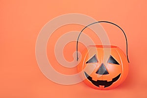 Happy Halloween Trick or Treat jack-o-lantern bucket on orange background. Plastic pumpkin  to collect candy.