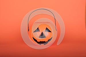 Happy Halloween Trick or Treat jack-o-lantern bucket on orange background. Plastic pumpkin  to collect candy.