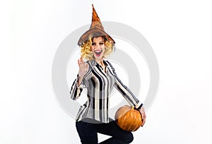 Happy Halloween witch with pumpkin waving hand. Smiling Halloween party girl in witch hat with big pumpkin. Happy