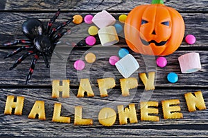 Happy Halloween words decoration with scary spider, candy and pumpkin on wooden background