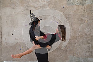 Happy halloween. Young beautiful woman and girl dressed as witches on grey background are having fun and having a good time. They