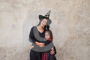 Happy halloween. Young beautiful woman and girl dressed as witches on grey background are having fun and having a good time. They