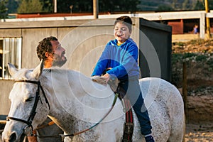 Happy handicapped boy riding a horse during equine therapy