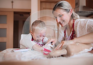 A happy handicapped down syndrome child with his mother indoors baking.