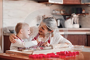 A happy handicapped down syndrome child with his mother indoors baking.