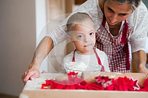 A happy handicapped down syndrome child with his mother indoors baking.