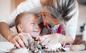 A happy handicapped down syndrome child with his mother indoors baking.