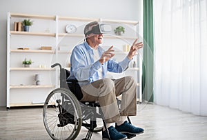 Happy handicapped senior man in wheelchair using VR headset to explore augmented reality at home