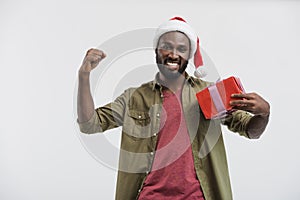 happy handsome african american man in santa hat gesturing and holding present