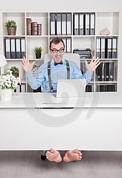 Happy handsome barefoot business man in office