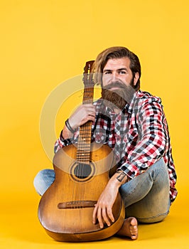 Happy handsome bearded guy with unshaven face and stylish hairdo wear casual clothes play guitar, musician