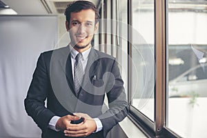 Happy handsome businessman standing and smiling in office