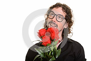 Happy handsome Caucasian man holding red roses while thinking re