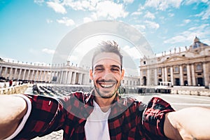 Happy handsome caucasian man take a selfie portrait in front of St. Peter's cathedral at Vatican City, Rome Italy