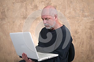 Happy handsome elderly casual man using computer, smiling. Portrait of a middle aged adult, older casual happy smiling, mature