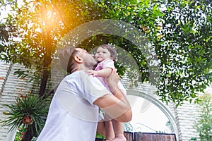 Happy handsome father kissing adorable little baby daughter with happiness and smile face. Single dad embrace and lifting his