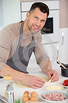 happy handsome man cooking in kitchen at home