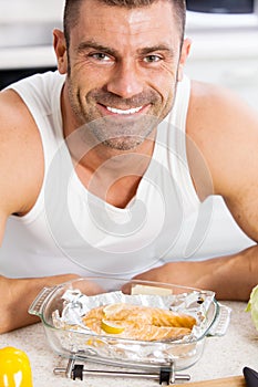 Happy handsome man cooking in kitchen at home.