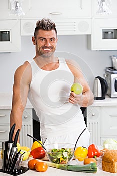 Happy handsome man cooking in kitchen at home.