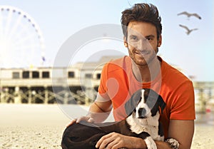 Happy handsome man with dog at seascape beach