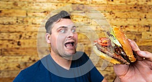 Happy handsome man with his fast food burger. Not so much healthy lifestyle, but whatever