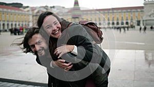 Happy handsome man holding joyful girlfriend on his back