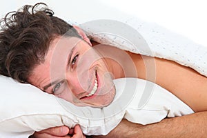 Happy handsome man lying in bed