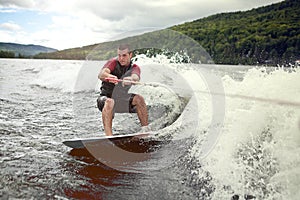 Happy handsome man wakesurfing in a lake