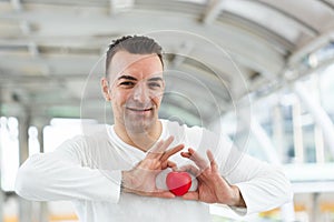 Happy handsome man white T-shirt and holding red heart. Happy health concept