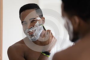 Happy handsome mixed race African man shaving with razor