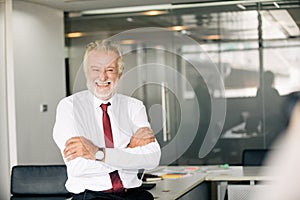 Happy handsome old businessman standing and smiling in office