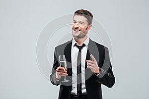 Happy handsome young businessman drinking champagne and pointing on you