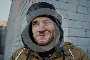 Happy handsome young man in cap with earflaps. The young man in the fur hat