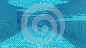 Happy handsome young man in the swimming pool, underwater view. Vacation summer time. Action camera