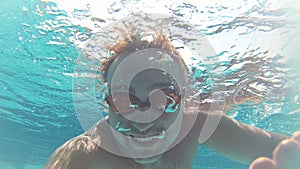 Happy handsome young man in the swimming pool, underwater view. Vacation summer time. Action camera