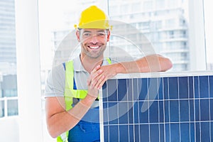 Happy handyman with solar panel in bright office