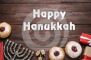 Happy Hanukkah. Traditional menorah, candles, sufganiyot and dreidels on wooden background, flat lay