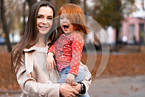 Happy harmonious family concept. Young mother and child daughter with red hair, together, hugging and joyfully laughing