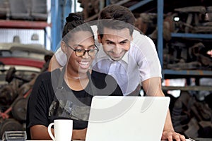 Happy harmony people work together at workplace, smiling African American woman working on laptop computer with colleague guy at